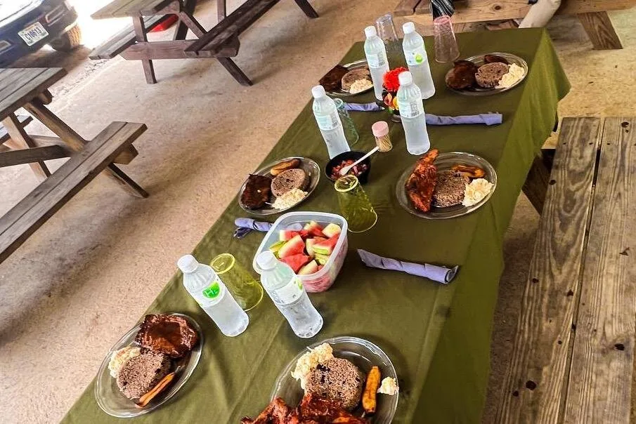 Ein Picknicktisch mit Tellern voller belizischer Gerichte, Obst und Wasserflaschen