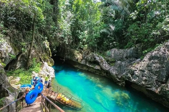 Ein türkisfarbener Flusspool in einer Dschungelschlucht mit Reifen neben einem Holzsteg